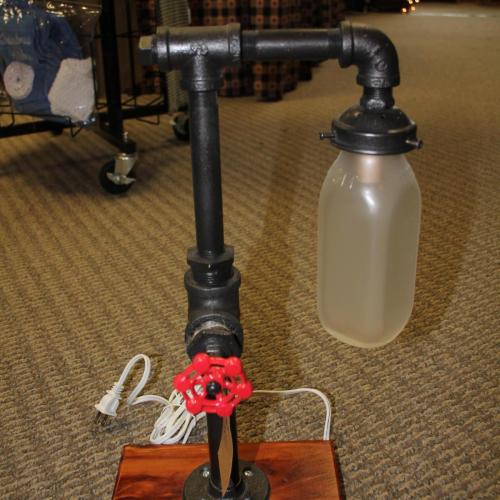 Pipe Lamp with red garden hose handle and milk bottle shade